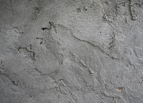 Değişik dokular, tanecikli detaylar ve ince kusurlar içeren pürüzlü, düzensiz, gri beton bir yüzeyin yakın çekim, tam kare görüntüsü.
