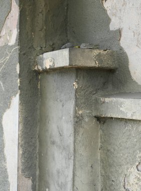 Yakından bakınca, kabuğu soyulmuş bir duvar ve pürüzlü bir doku görünüyor. Göze çarpan bir çimento yapısı var. Işık ayrıntıları açıkça yakalıyor.