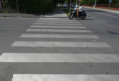 UZHOROD, UKRAINE - EYLÜL 03, 2025: Motosiklet Uzhhorod 'da sakin bir caddede işaretli bir yaya geçidinden geçiyor