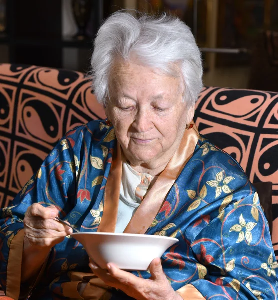 Alte Frau isst zu Hause — Stockfoto