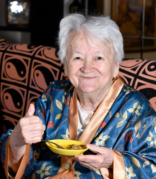 Old woman eating at home — Stock Photo, Image