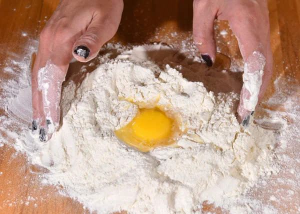 Frau fügt Ei zum Mehl hinzu — Stockfoto