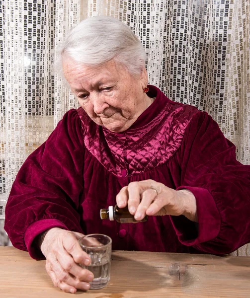 Vecchia donna gocciolante medicina — Foto Stock