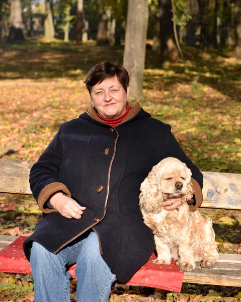 Старшая женщина сидит на скамейке с собакой — стоковое фото