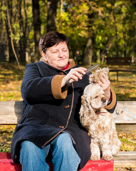 Bir köpek ile bir bankta oturan kadın kıdemli — Stok fotoğraf