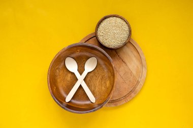 Çevre dostu sofra takımı. Ahşap kase, tabaklar, sarı arka planda kaşık. Geri dönüşüm konsepti. Üst görünüm.