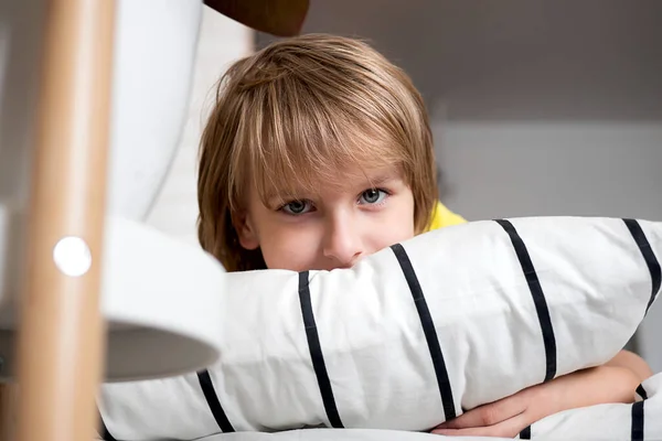 Blondyn w żółtej koszulce leży na łóżku i bawi się w domu — Zdjęcie stockowe