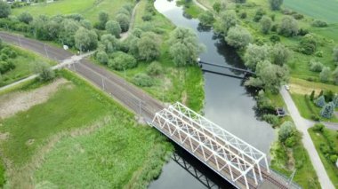 Motawa Nehri yeşil alanlar ve bir demiryolu köprüsü arasında sorunsuzca akar. Polonya.
