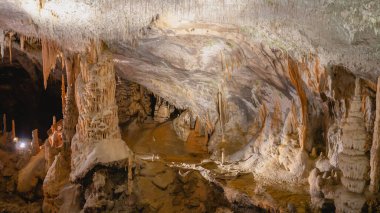 Postojna mağarası, Slovenya ve Avrupa 'daki dev sarkıtlar, dikitler ve dikdörtgenlerle büyük mağaralardaki turistler için harika bir geçiş resmi..