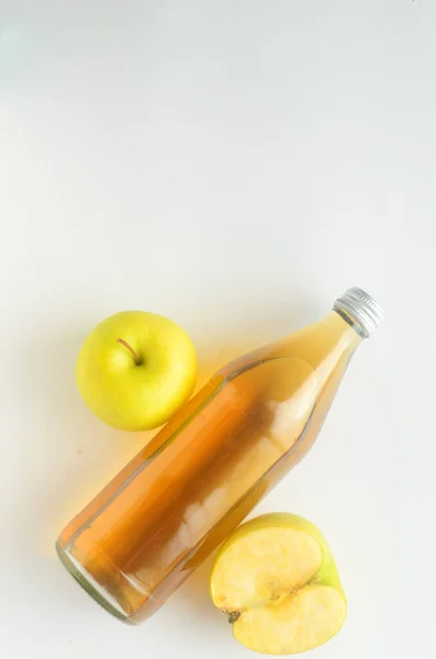 Vista superior, una botella de vinagre de sidra de manzana y manzanas verdes sobre fondo blanco. — Foto de Stock