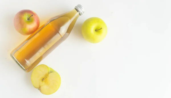 Vista superior, una botella de vinagre de sidra de manzana y dos manzanas y media sobre fondo blanco, copyspace. — Foto de Stock