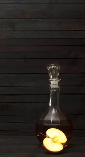 Un decantador con vinagre de manzana y media manzana sobre fondo de madera oscura. — Foto de Stock