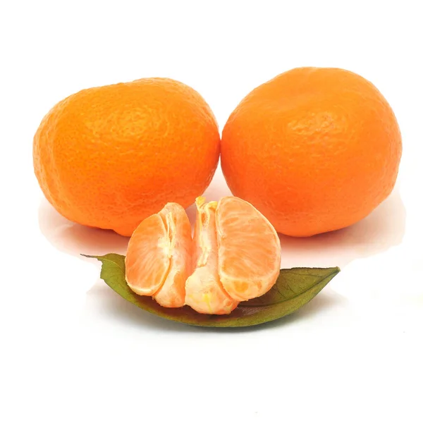 Tranches de mandarine sur une feuille et deux mandarines entières isolées sur fond blanc — Photo