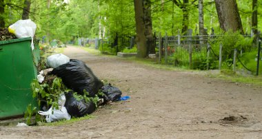 Bir konteynır dolusu çöp ve yakınlarda bir sürü çöp var. Mezarlıkta değil.