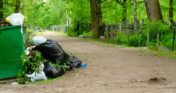 Bir konteynır dolusu çöp ve yakınlarda bir sürü çöp var. Mezarlıkta değil.