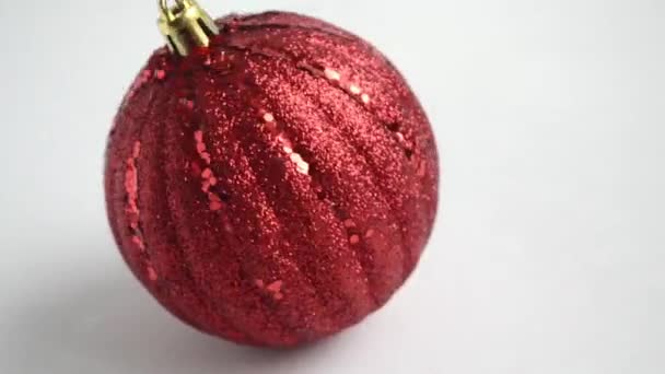 Κόκκινη χριστουγεννιάτικη μπάλα αιωρείται σε μια λευκή επιφάνεια, κοντά. — Αρχείο Βίντεο