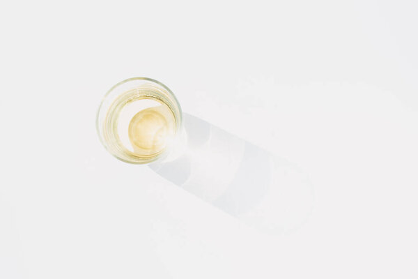 Creative photo of a simple clear wine glass on a white background with sunlight and harsh shadows.