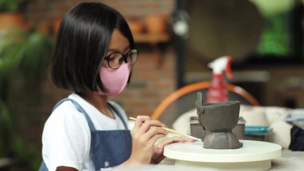 Sidovy porträtt av söt flicka gör lera verkstad genom att måla potten i klassrummet — Stockvideo