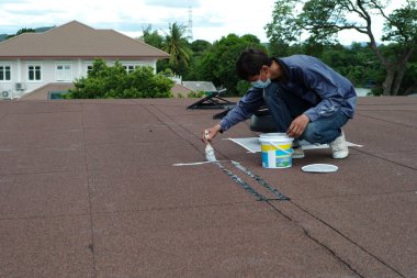 Motion blurred worker fixing and sealing the surface of the roof