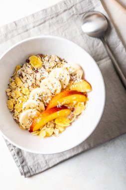 Koyu beyaz bir tabakta taze meyvelerle süslenmiş kahvaltılık granola.