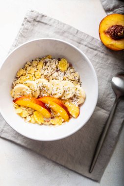 Koyu beyaz bir tabakta taze meyvelerle süslenmiş kahvaltılık granola.