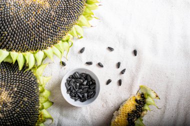 Masa örtüsüyle kaplı bir masada ayçiçekleri, kasedeki tohumlar.