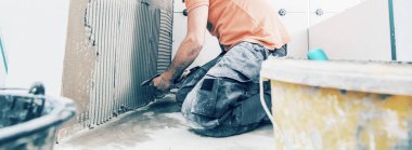 Geniş biçimli döşeme döşeyen profesyonellerin kırpılmış görüntüsü. konut yenileme konsepti