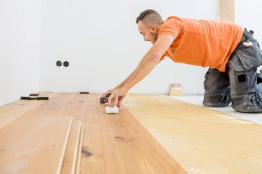 Erkek işçi inşaat alanına parke döşeme kuruyor. Parke döşeme  