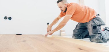 Erkek işçi inşaat alanına parke döşeme kuruyor. Parke döşeme  