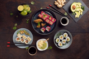 Lezzetli ruloların üst görüntüsü, suşi ve siyah kırsal arka planda çubukları olan maki. 