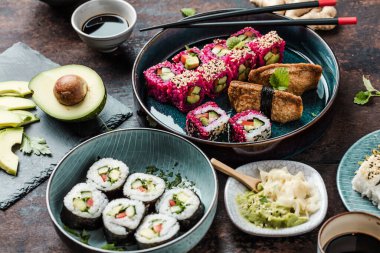 Gurme Asya dürümleri, suşi ve maki çubuklarla birlikte tahta bir tahtanın üzerinde. 
