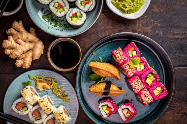 Lezzetli ruloların üst görüntüsü, suşi ve siyah kırsal arka planda çubukları olan maki. 