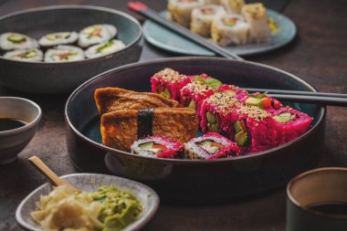 Yakın çekim o lezzetli rulo, suşi ve siyah kırsal arka planda yemek çubukları ile maki