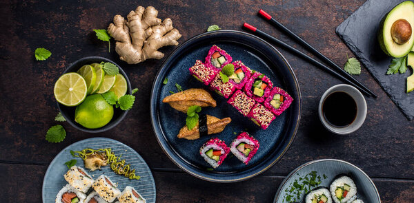 вид сверху на вкусные рулоны, суши и маки с палочками для еды на черном деревенском фоне 