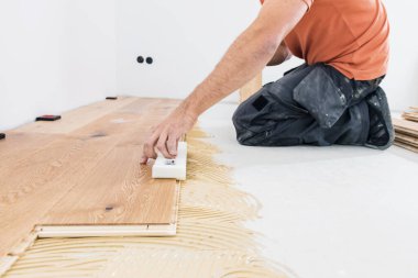 Erkek işçinin inşaat alanına parke döşeme kurarken çekilmiş görüntüleri. Parke döşeme   