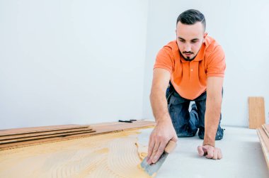 İnşaat alanına parke döşemesi kuran odaklanmış adamın yan görüntüsü