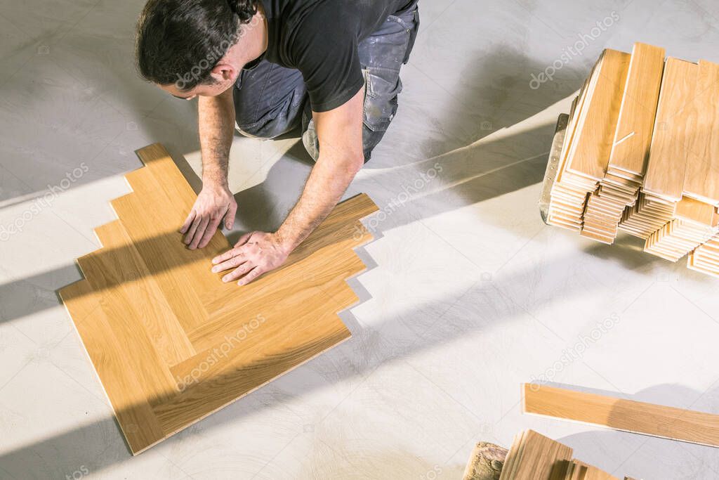 high angle view of man installing oak parquet floor during home improvement