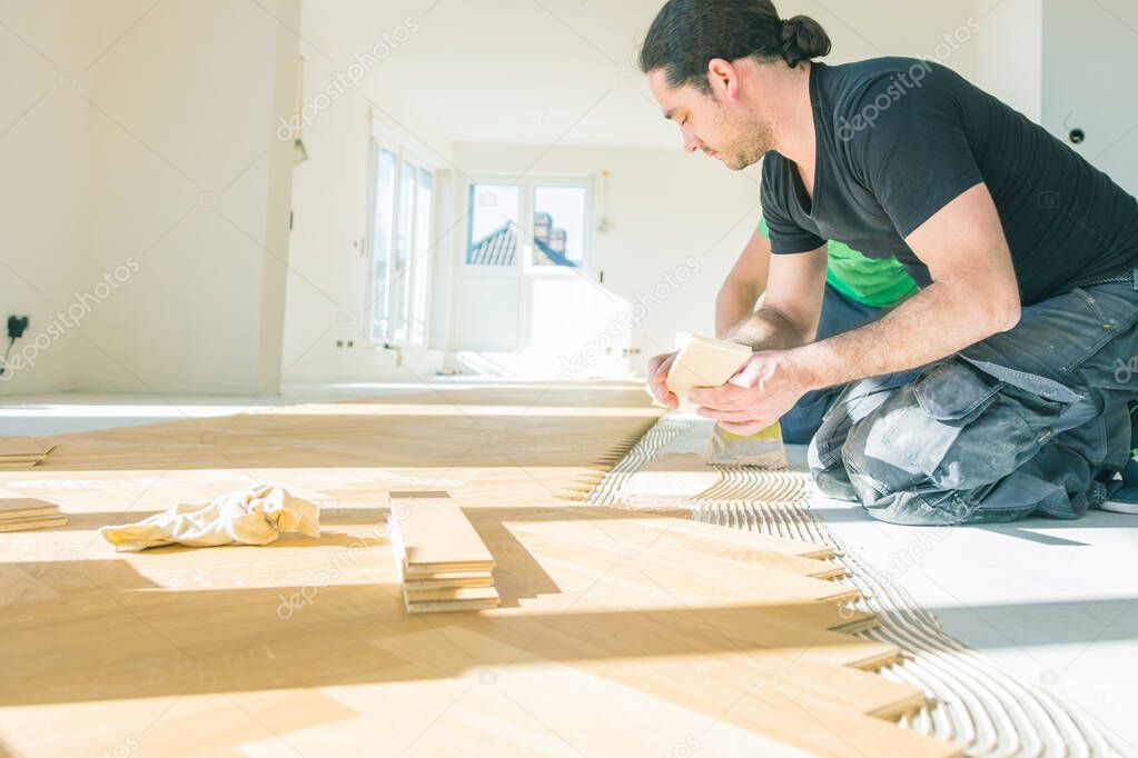 Male carpenters installing floor during home renovation. Repair, building and home concept