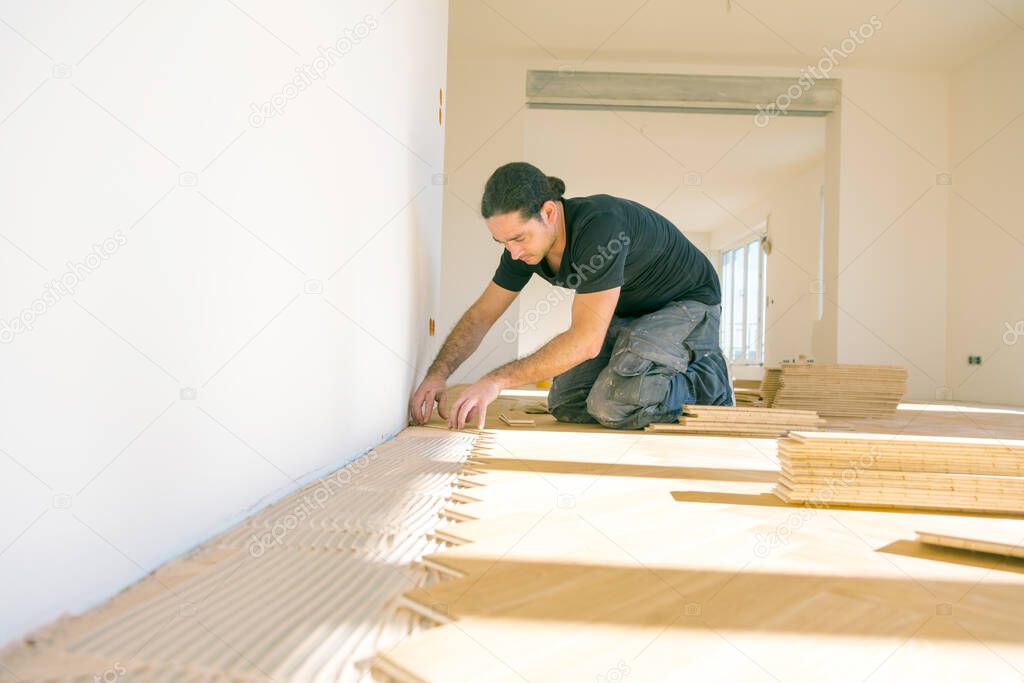 male worker installing parquet floor during home improvement