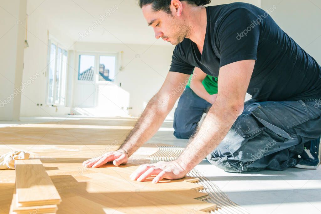 male worker grinding parquet floor during home improvement