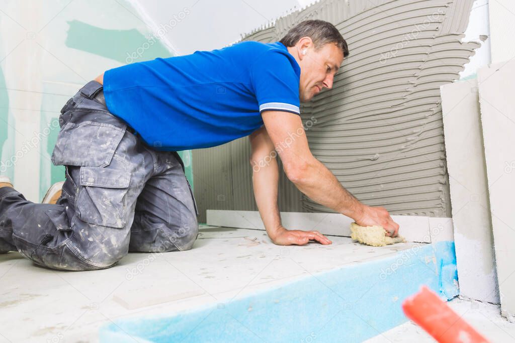 professional tiler installing large format tiles on wall. home indoors renovation 