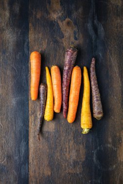 Tahta masada taze, çiğ gökkuşağı havucu manzarası. 