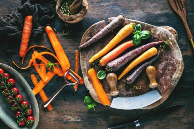 Tahta masadaki taze havuç, domates ve otların yakın plan görüntüsü.