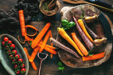 Tahta masadaki taze havuç, domates ve otların yakın plan görüntüsü.