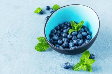 Mavi zemin üzerinde nane yapraklı taze yaban mersini.