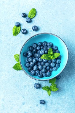 Mavi zemin üzerinde nane yapraklı taze yaban mersini.