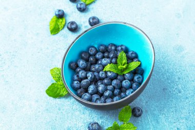 Mavi zemin üzerinde nane yapraklı taze yaban mersini.