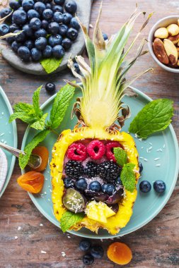 Yarısı ananas ve taze böğürtlenli gurme tatlısının üst görüntüsü.    