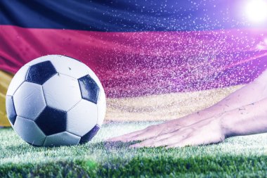 Kırpılmış erkek eli, Alman bayrağı ve yeşil çimlerin üzerinde futbol topu.