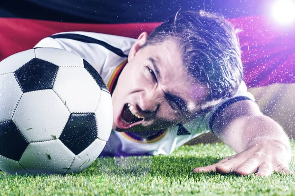 Emocjonujący Młody Mężczyzna Piłkarz Sięgający Piłkę Zielonej Trawie Stadionu Flaga — Zdjęcie stockowe